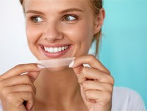 woman holding teeth whitening strip 