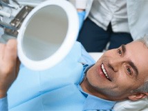 a man viewing his smile in a mirror at a dental office 