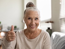 woman giving thumbs up after getting all-on-4 dental implants 