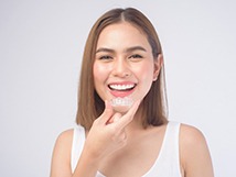 patient smiling while holding clear aligner 