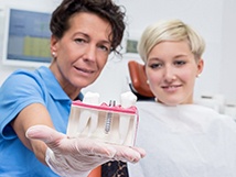 Implant dentist showing model to patients