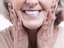 Closeup of older woman smiling with hands on face