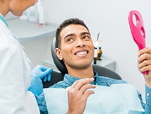 Young man smiles with dental mirror in hand