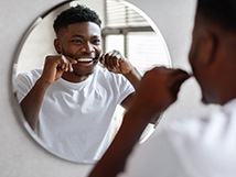 Smiling man flossing his teeth