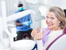 Older woman with two thumbs up in dental chair