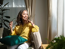 a woman sitting in her living room and holding her glasses