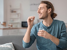 a man taking a pill and holding a glass of water