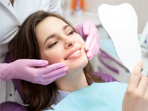 patient smiling while looking in dental mirror 