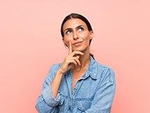 Woman thinking with hand on chin and pink background