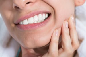 Woman with hand on her cheek due to tooth sensitivity