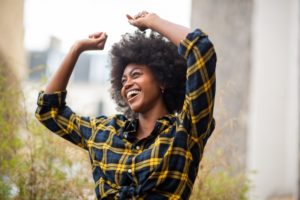 Woman smiling outside with hands above her head