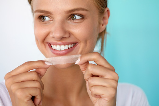 young woman holding whitening strips 