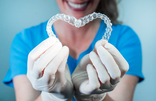 dentist holding clear aligners in a heart