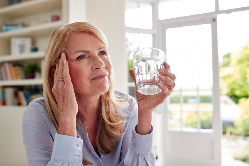 woman holding water glass and her head
